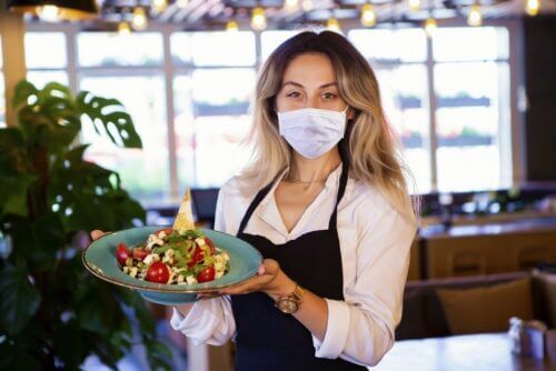 Waitress Wearing a Mask Holding Plate of Food